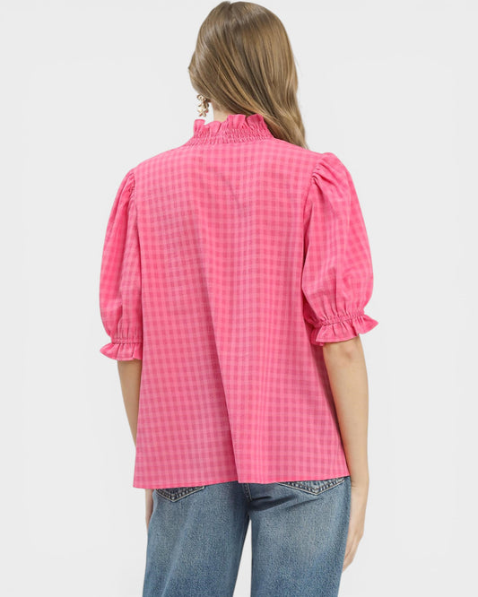 Person wearing a pink checkered blouse with puffed sleeves on a white background