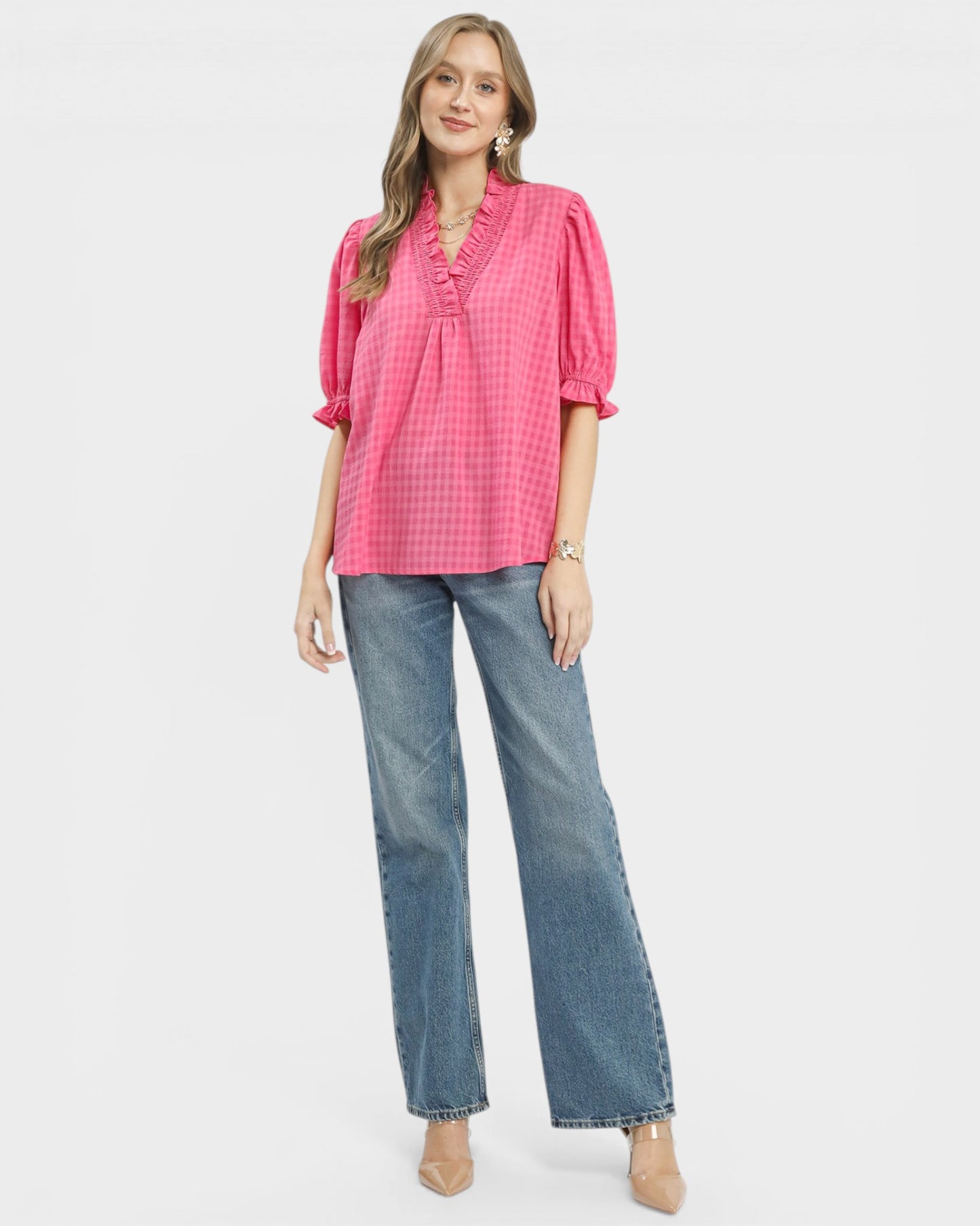 Woman wearing a pink checkered blouse and blue jeans on a white background