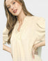 Woman wearing a beige blouse with a plain background
