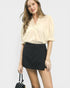 Woman wearing a beige blouse and black skirt on a white background