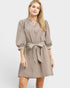 Woman wearing a beige dress with a striped belt on a white background
