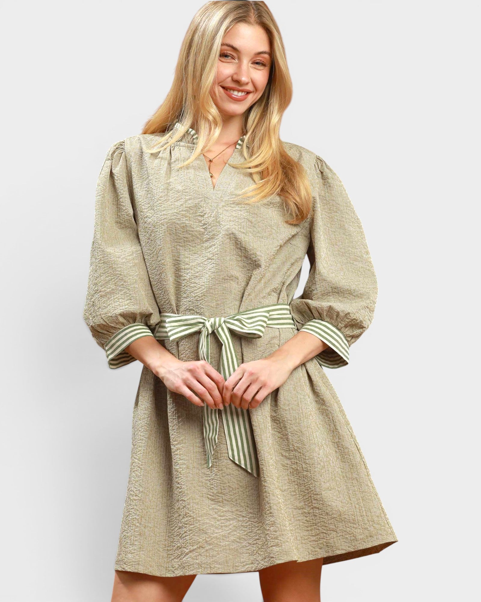 Woman wearing a beige dress with a belt on a white background