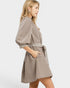 Woman wearing a beige dress with striped belt on a white background