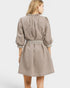 Woman wearing a beige dress with striped trim on a white background