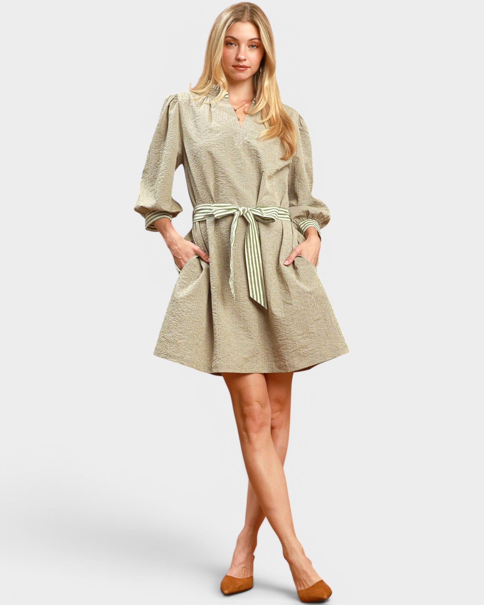 Woman wearing a beige dress with a belt on a white background