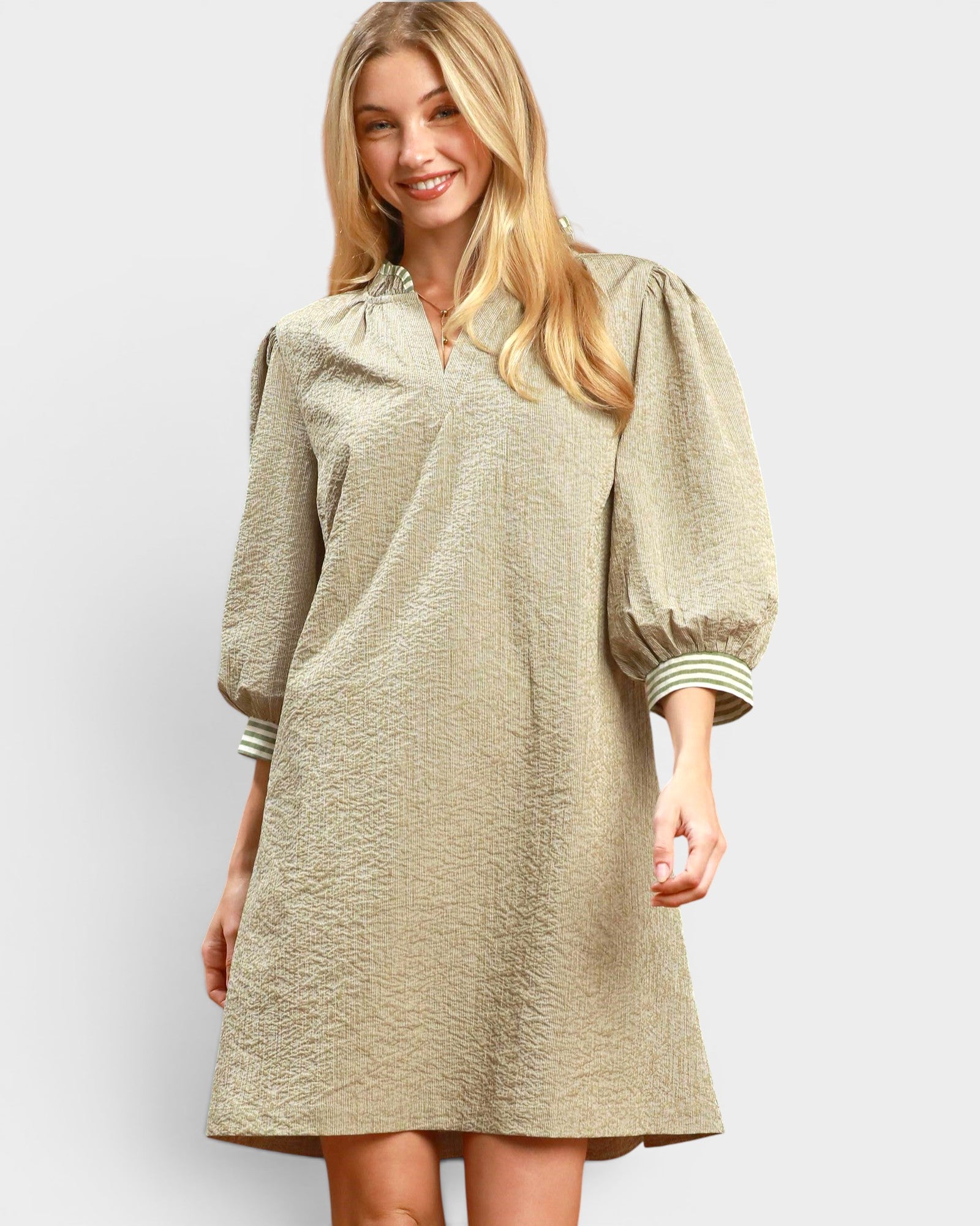 Woman wearing a beige dress with puffed sleeves on a white background