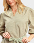 Woman wearing a green dress with a striped belt against a white background