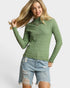 Woman wearing a green textured sweater and denim shorts on a white background