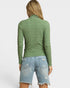Person wearing a green textured sweater and denim shorts on a white background