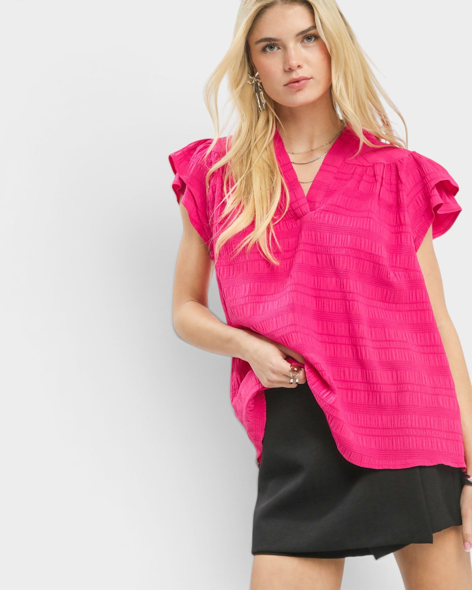 Woman wearing a bright pink blouse with ruffled sleeves on a white background