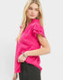 Woman wearing a bright pink blouse with ruffled sleeves on a white background