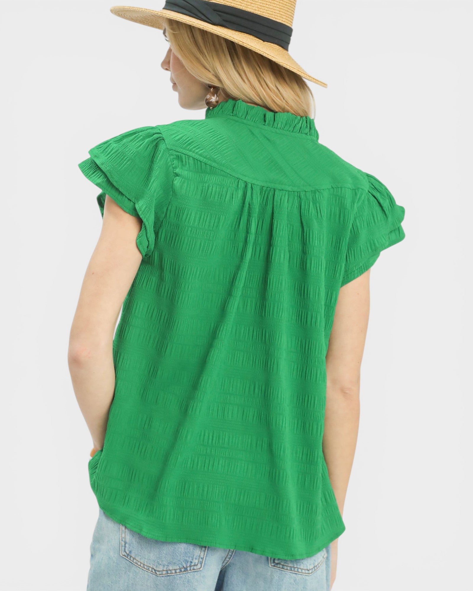 Person wearing a green sleeveless top and straw hat on a white background