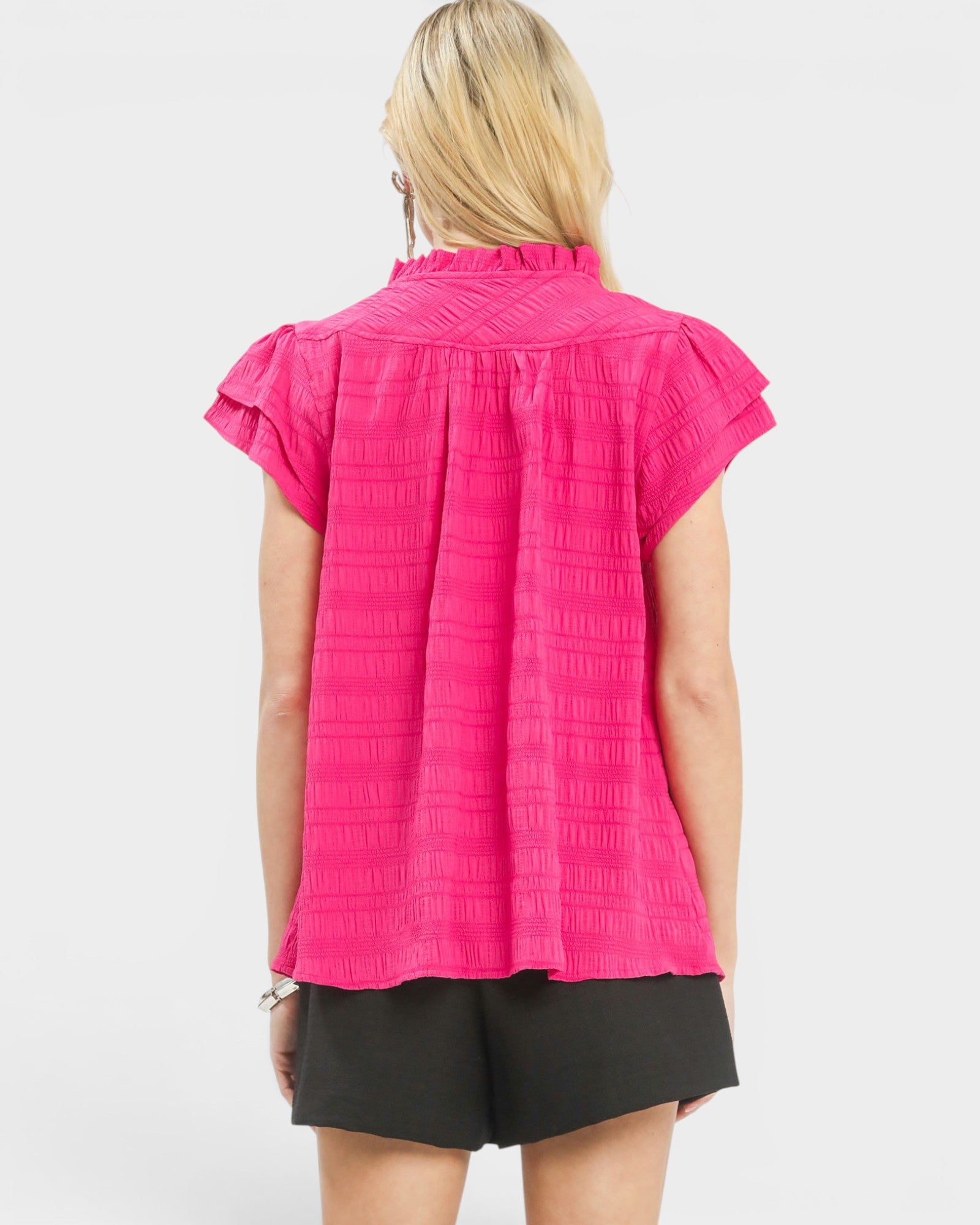 Person wearing a bright pink sleeveless top with a white background