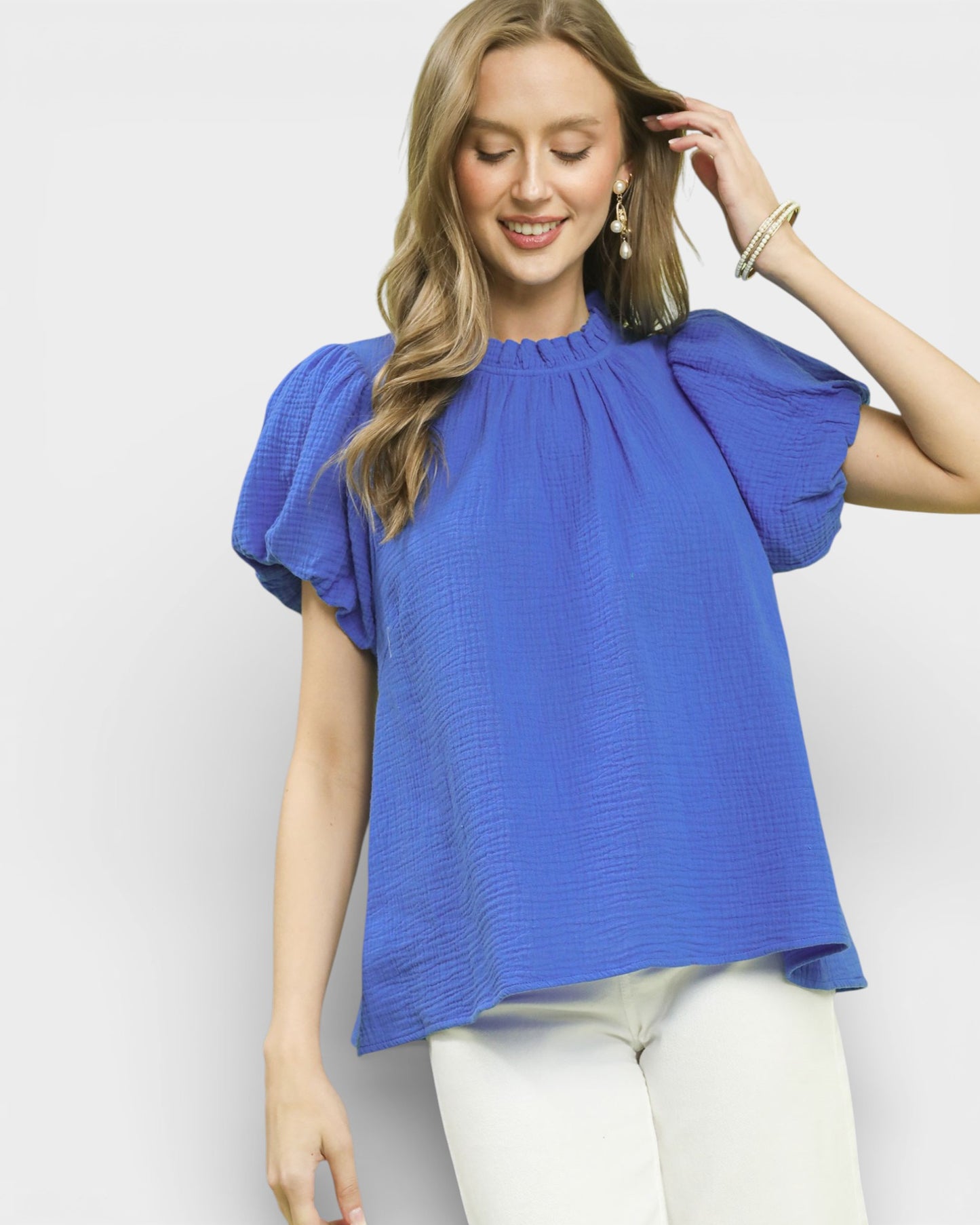 Woman wearing a blue blouse with ruffled sleeves on a white background