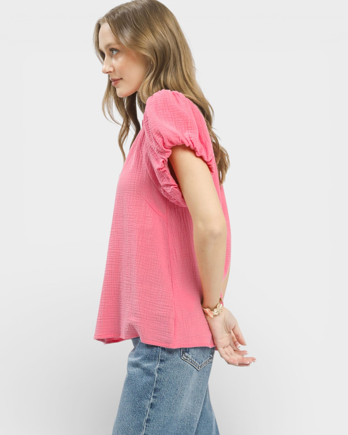 Woman wearing a pink blouse and blue jeans on a white background