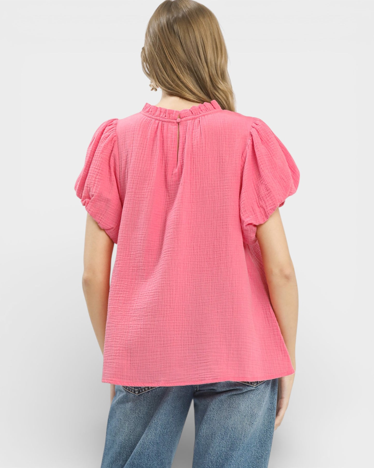 Person wearing a pink textured blouse with short sleeves on a white background