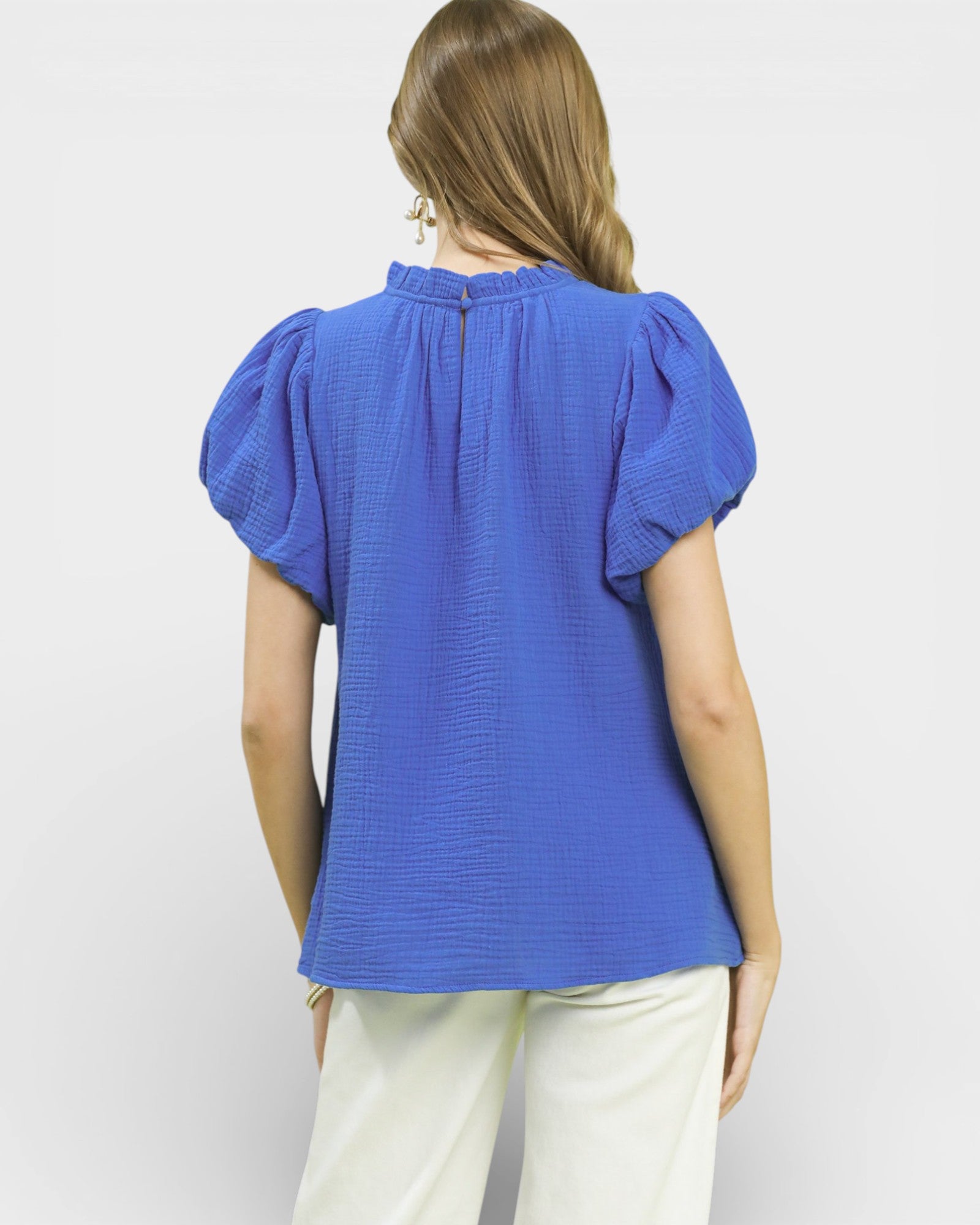 Woman wearing a blue blouse with puffed sleeves on a white background