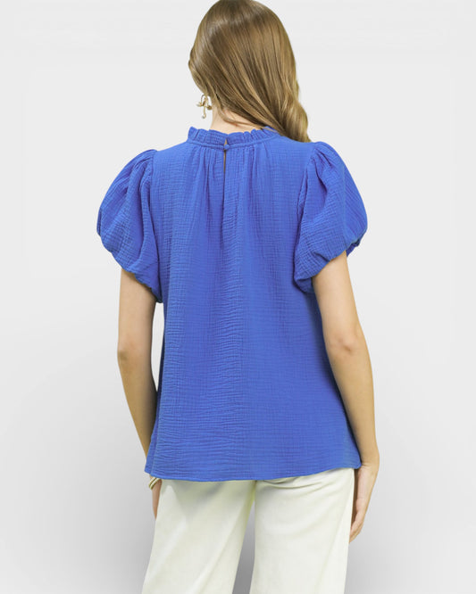 Woman wearing a blue blouse with puffed sleeves on a white background