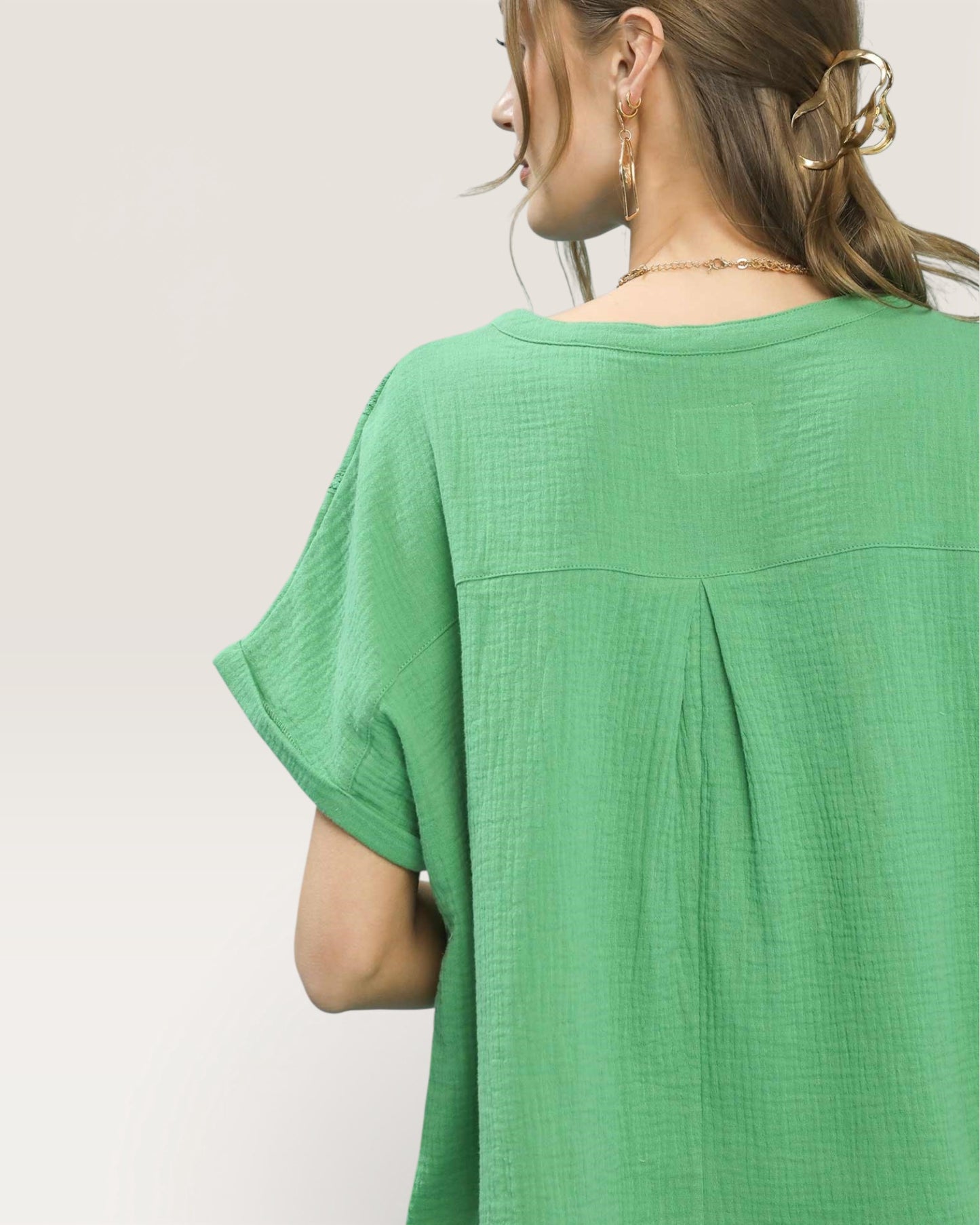 Green top worn by a person on a plain background