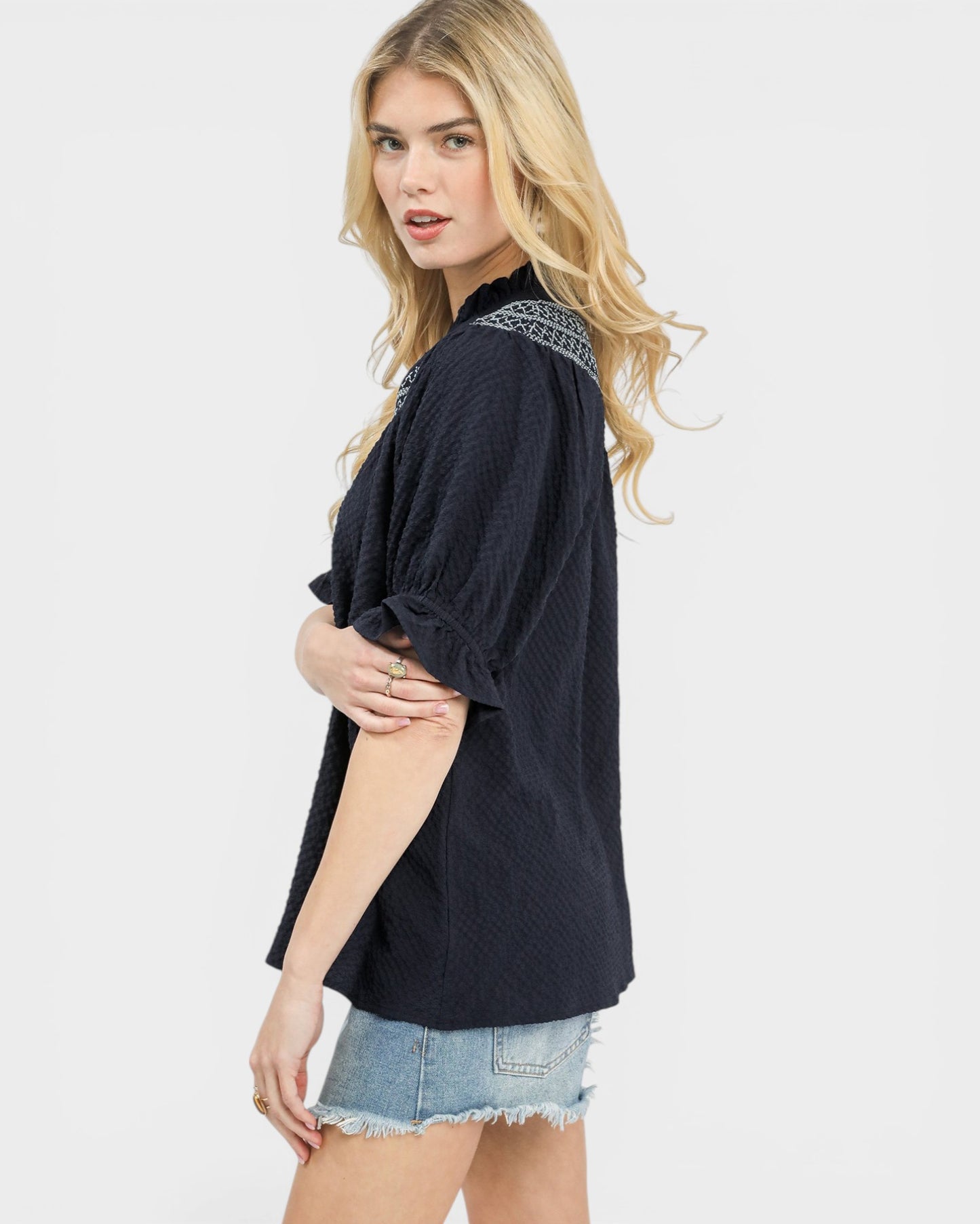 Woman wearing a dark blue blouse with lace details on a white background