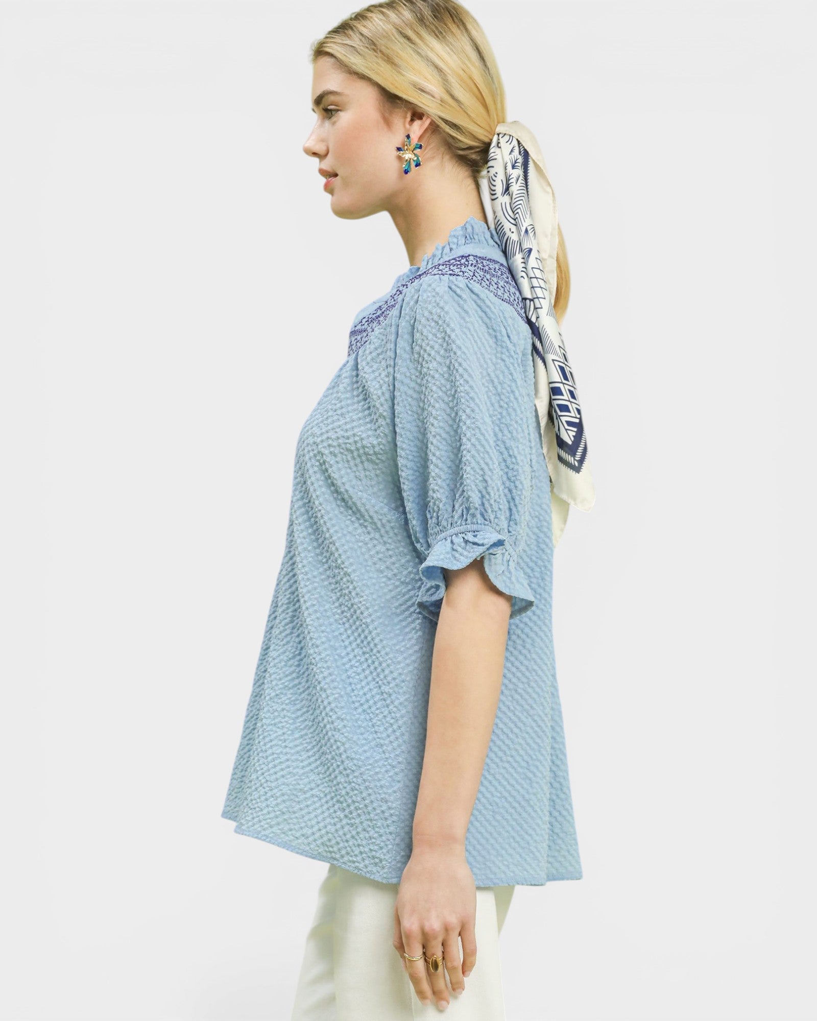 Woman wearing a light blue patterned blouse with a white background