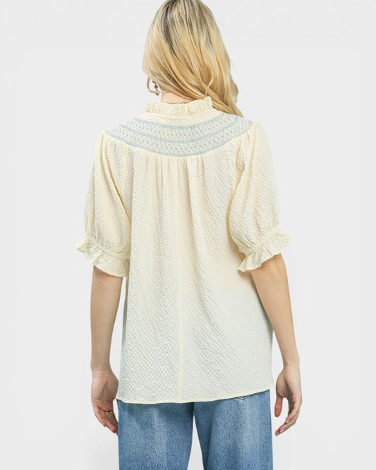 Woman wearing a light-colored blouse with lace details on a white background