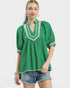 Woman wearing a green blouse with white trim on a white background