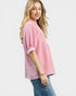 Woman wearing a pink textured top and blue jeans on a white background
