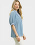 Woman wearing a light blue textured top on a white background
