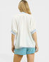 Woman wearing a white textured kimono-style top with blue trim and light blue shorts on a white background