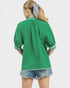 Person wearing a green mesh top and denim shorts on a white background
