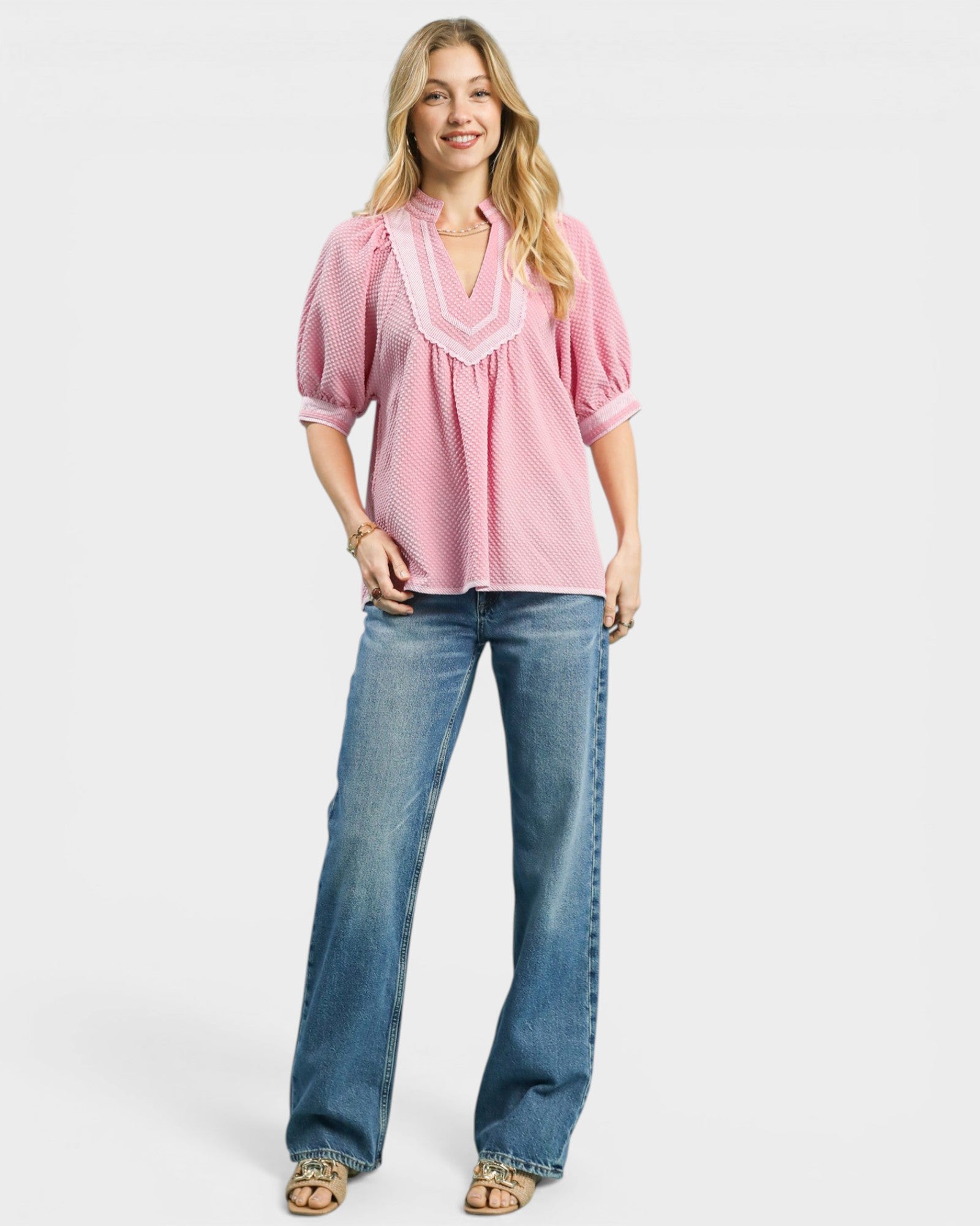 Woman wearing a pink blouse and blue jeans on a white background