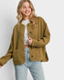 Woman wearing a mustard yellow jacket and light blue jeans on a white background