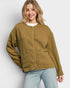 Woman wearing a green jacket and light blue jeans against a white background