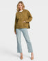 Woman wearing a green jacket and light blue jeans on a white background