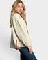 Woman wearing a cream sweater and blue jeans on a white background