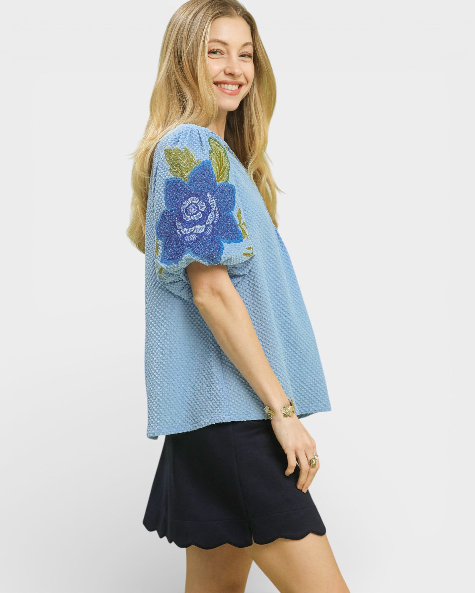 Woman wearing a blue top with floral design on a white background