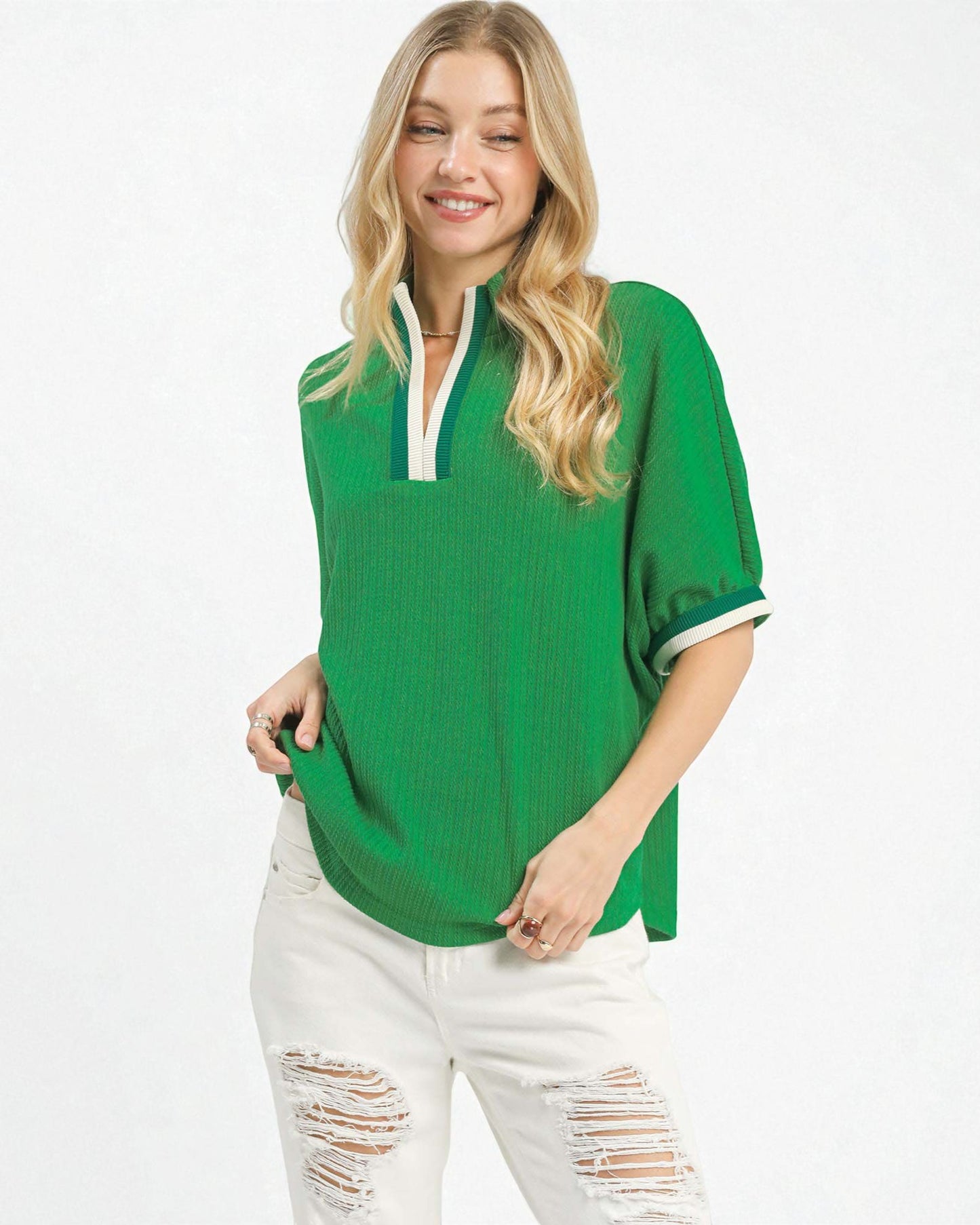 Woman wearing a green oversized shirt with white trim on a white background