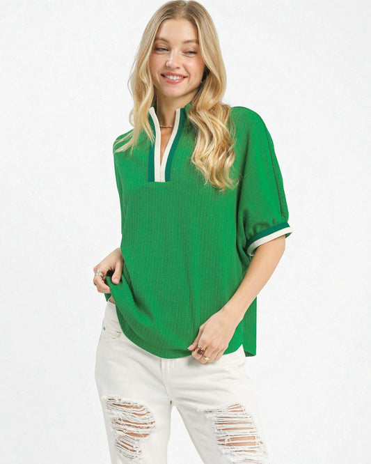 Woman wearing a green oversized shirt with white trim on a white background