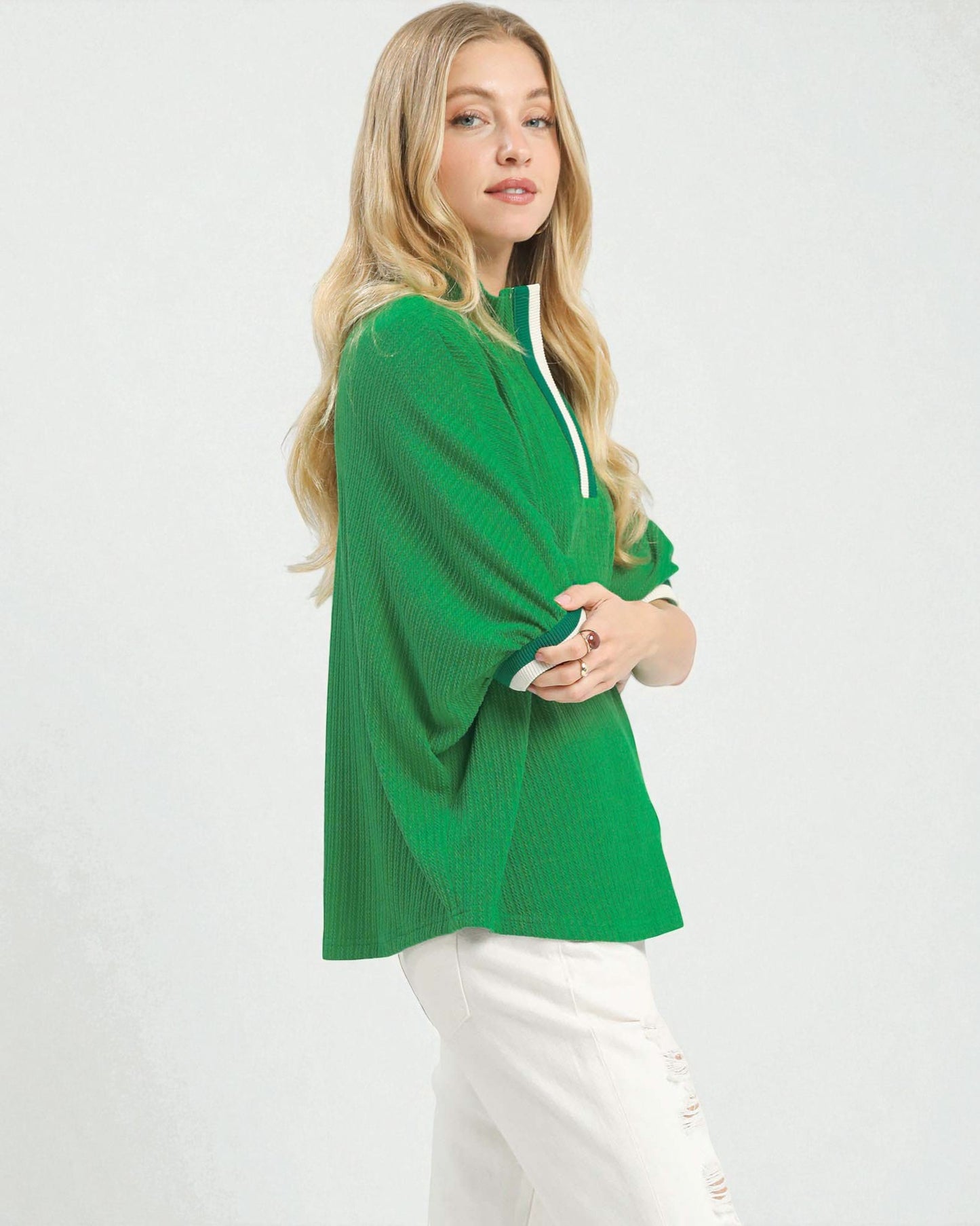 Woman wearing a green sweater and white pants on a white background