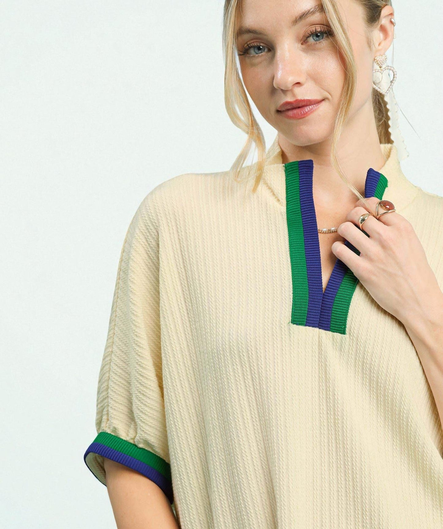 Woman wearing a beige dress with green and blue accents on a white background