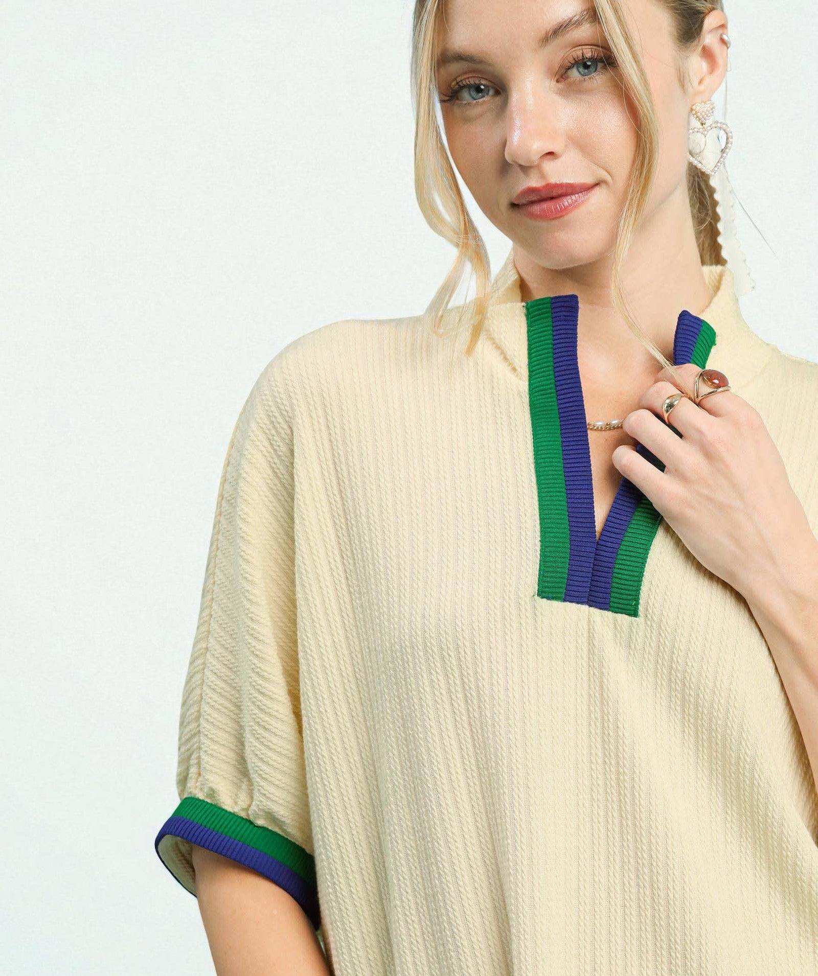 Woman wearing a beige dress with green and blue accents on a white background