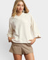 Woman wearing a cream-colored top and beige shorts on a white background