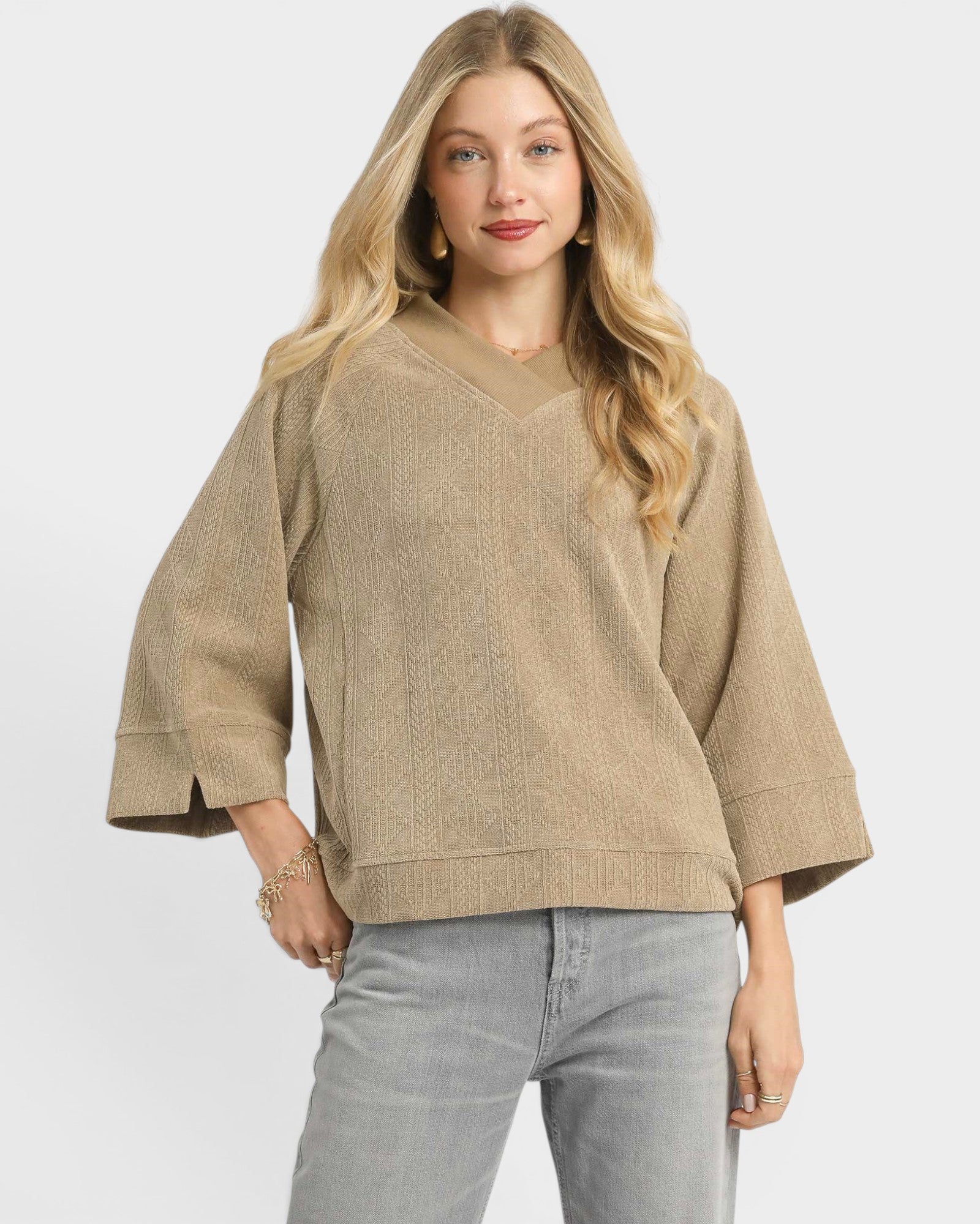 Woman wearing a beige sweater and gray pants on a white background
