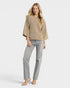 Woman wearing a beige sweater and gray jeans on a white background