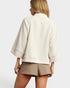 Woman wearing a beige top and shorts on a plain background