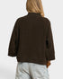 Person wearing a brown sweater and light blue jeans on a white background