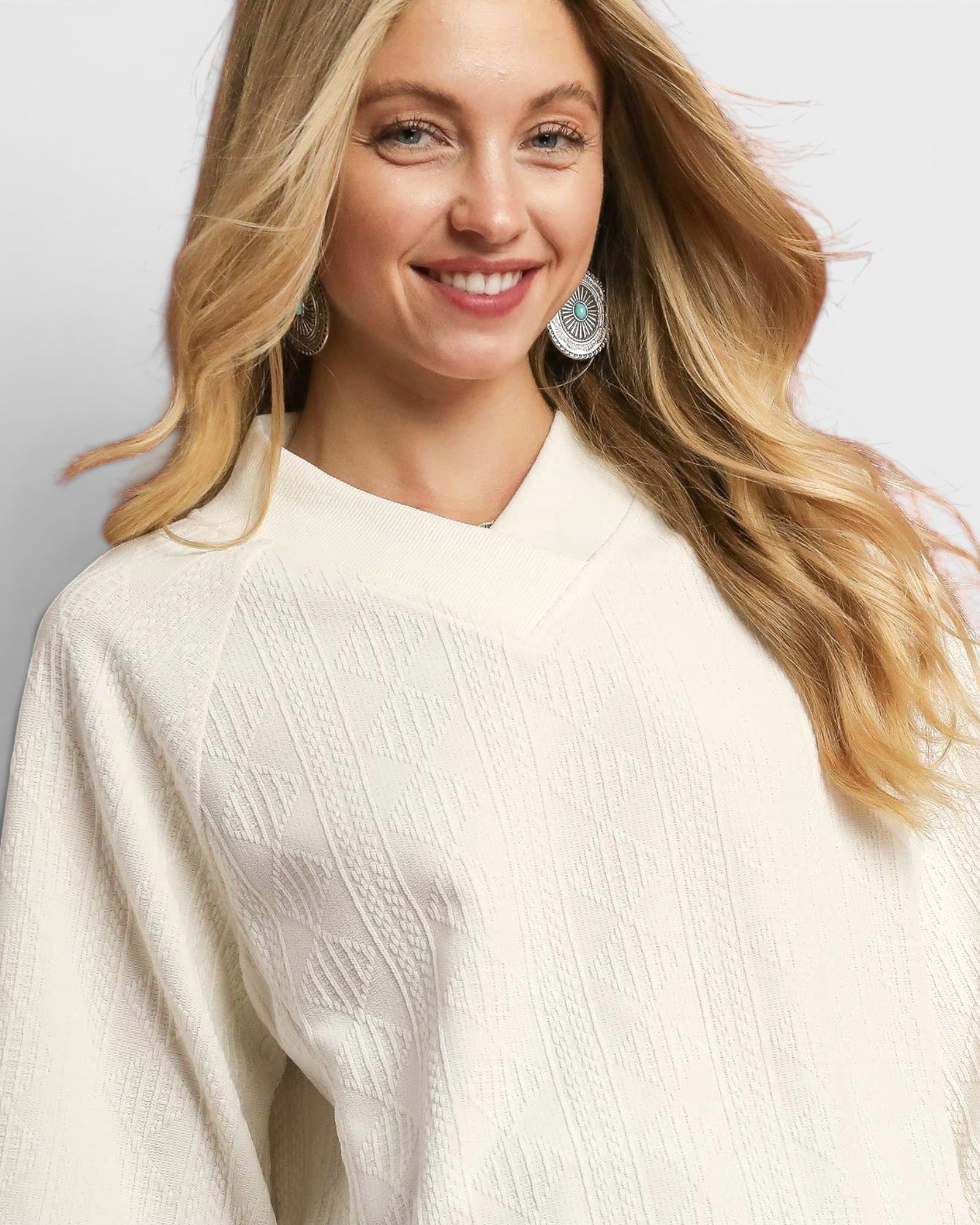 Woman wearing a white sweater with a plain background