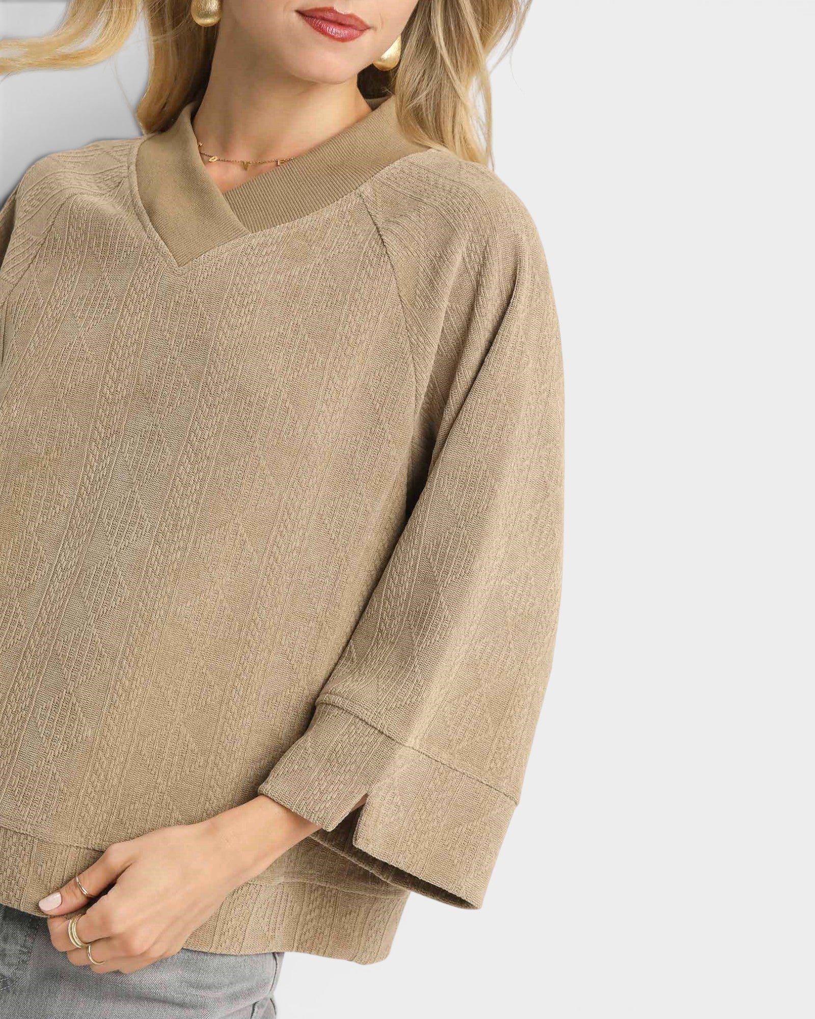 Beige sweater worn by a person on a white background