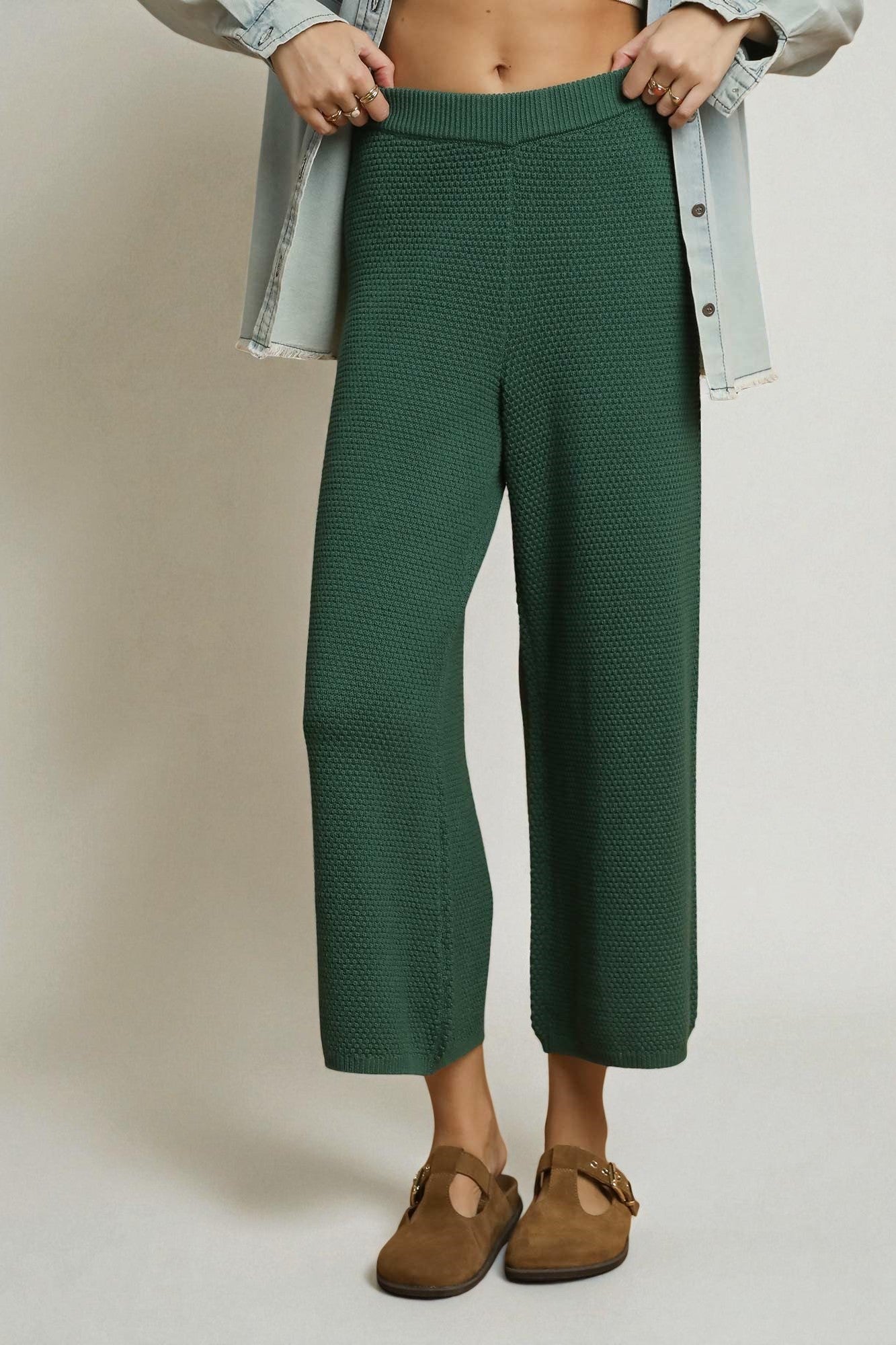 Person wearing green textured pants with a plain background